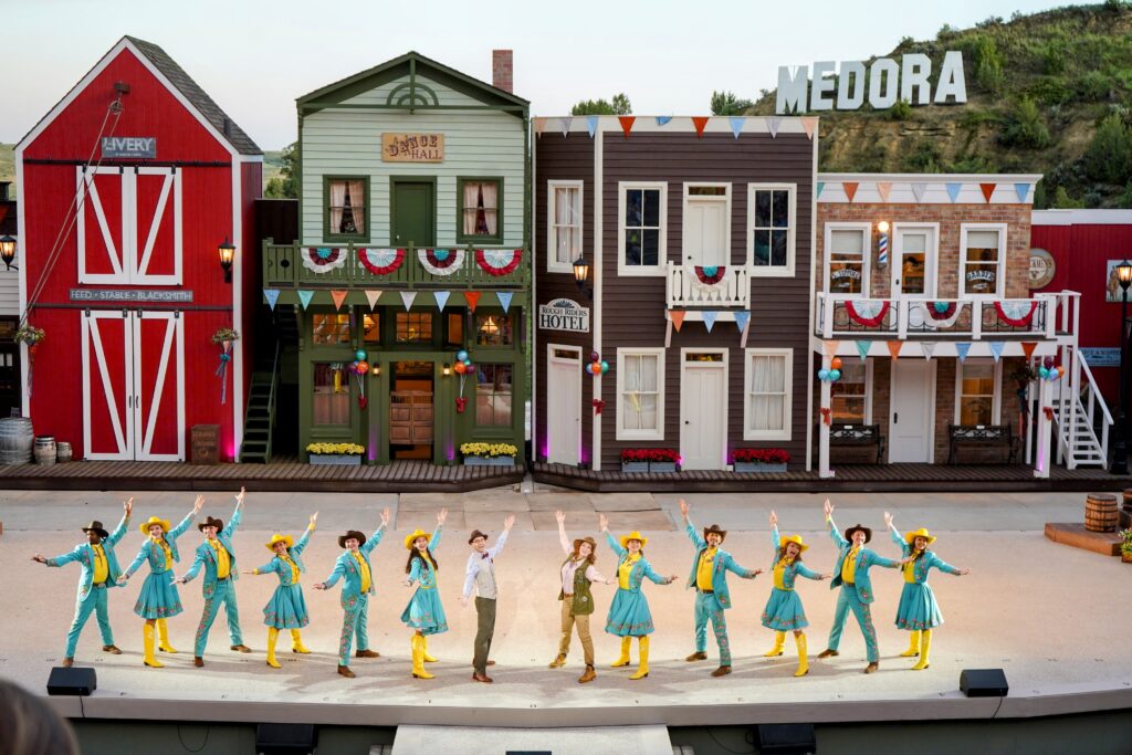 A view of the Medora Musical with performers and Medora in the background for your Theodore Roosevelt National Park Itinerary