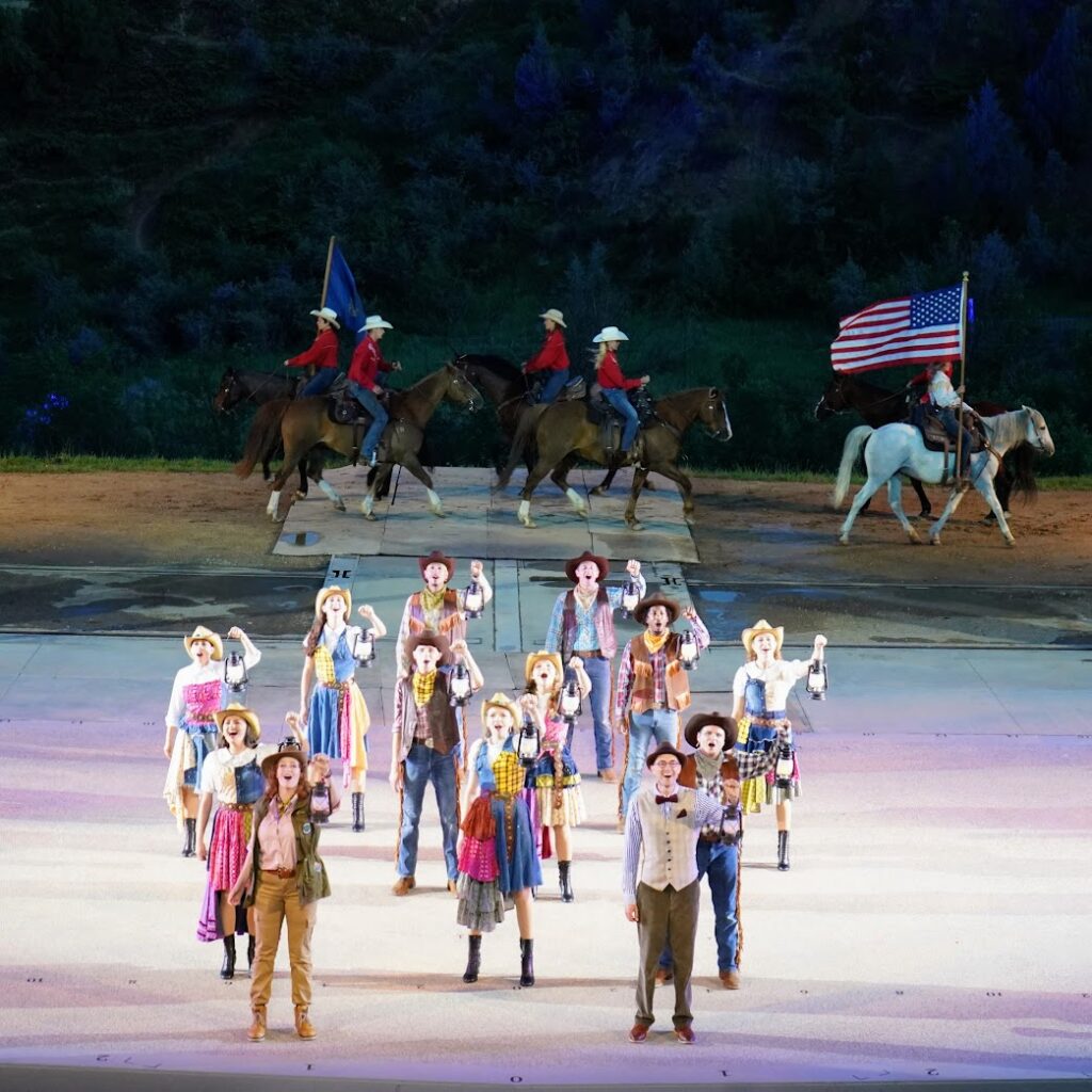 People dancing with horses and the American flag in the background at the Medora Musical 