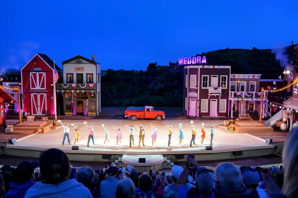 The Medora Musical at night with performers and the Medora sign lit up 
