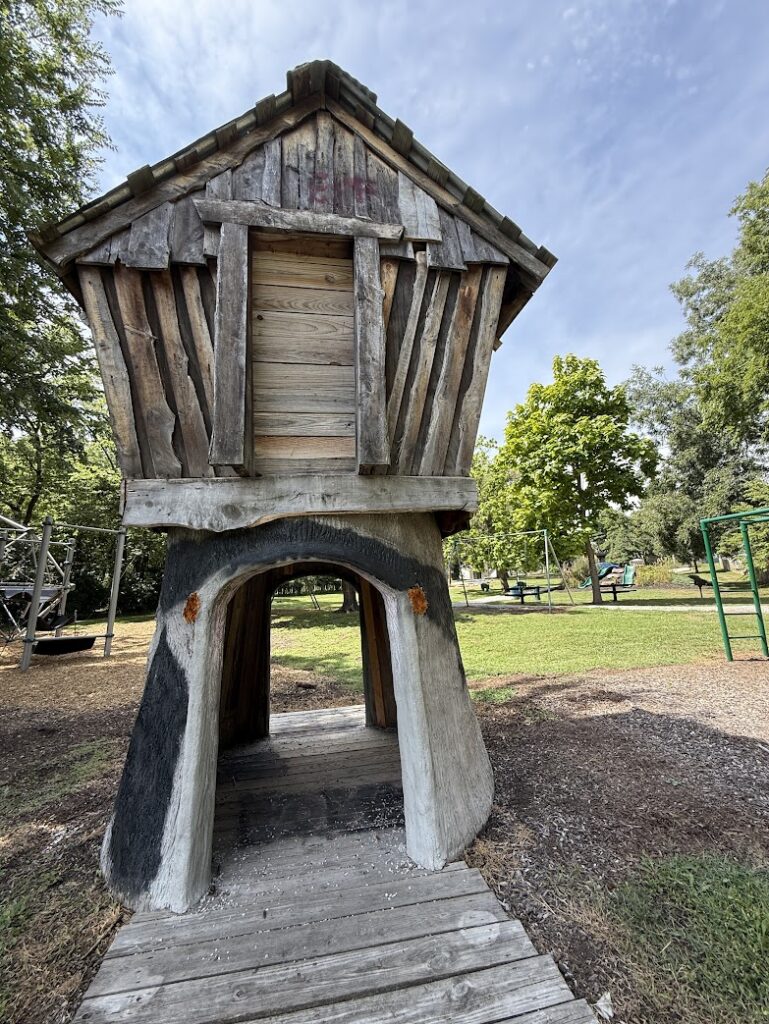 Rustic log-style structure surrounded by green space.