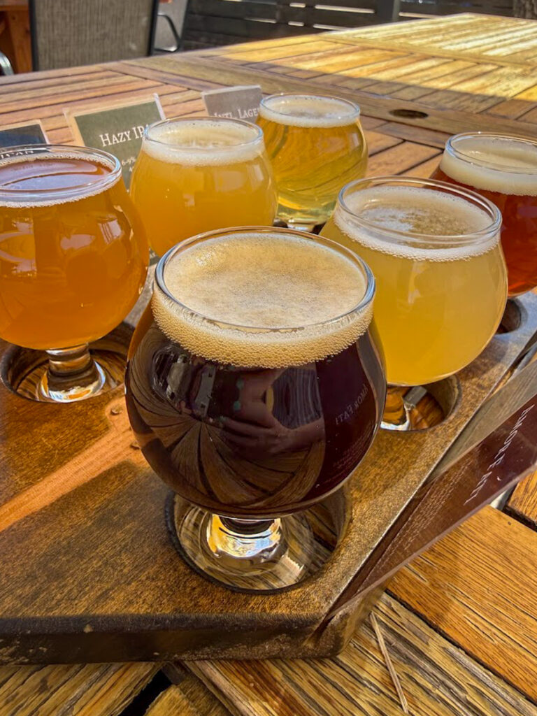 Gluten free friendly beer flight on wooden paddle at Bentonville brewery with labeled craft beers