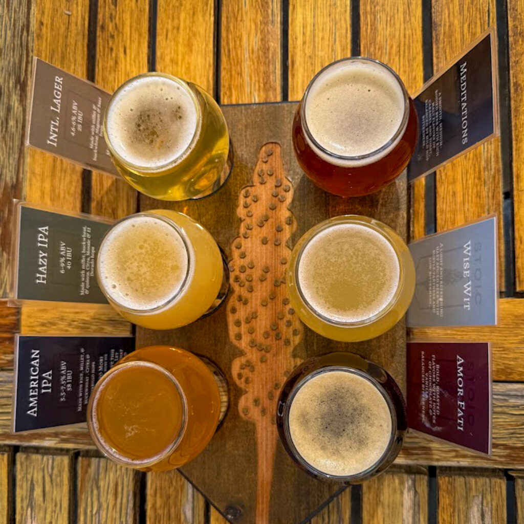 Gluten free friendly beer flight on wooden paddle at Bentonville brewery with labeled craft beers