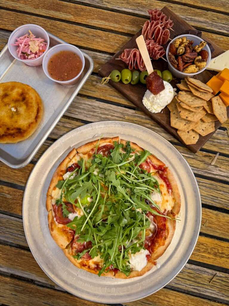 Gluten free pizza with arugula and charcuterie board at Bentonville restaurant outdoor dining