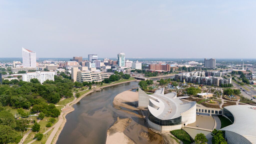 Aerial view of downtown Wichita showcasing the Arkansas River, Exploration Place, riverfront trails, and the city's skyline.