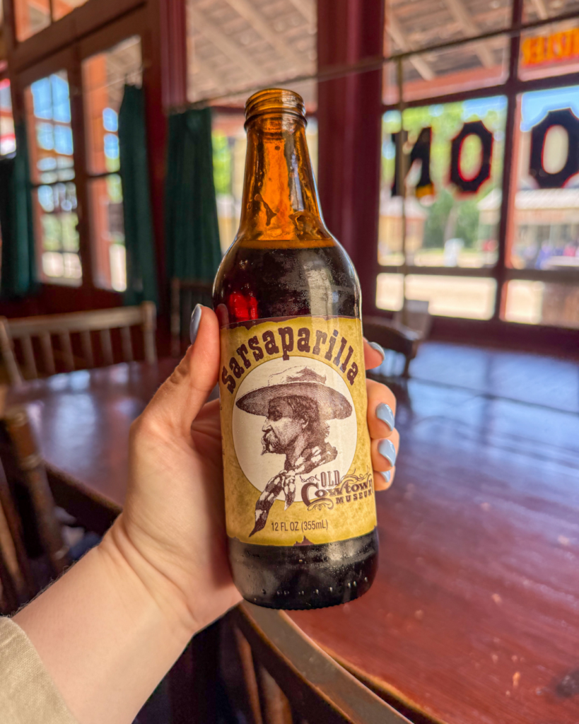 A bottle of old-fashioned sarsaparilla sits inside a historic saloon, offering visitors a taste of the American frontier experience.